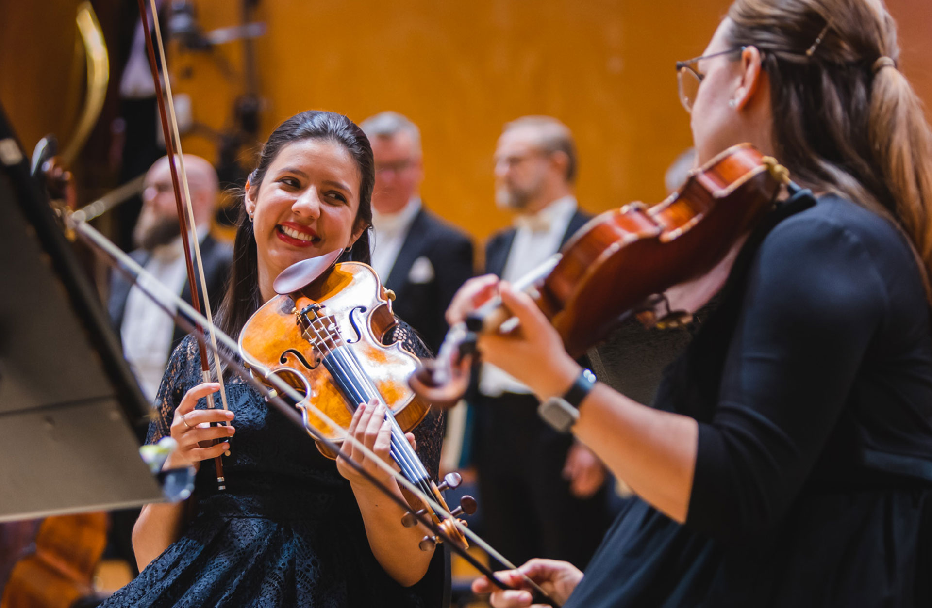 Glada violinister tittar på varandra på scenen.