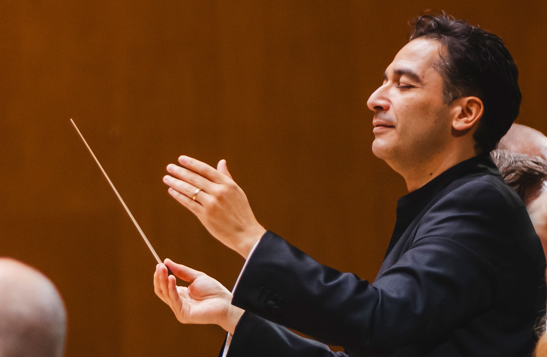 porträtt av Andrés Orozco-Estrada som dirigerar. Han njuter av musiken med stängda ögon.