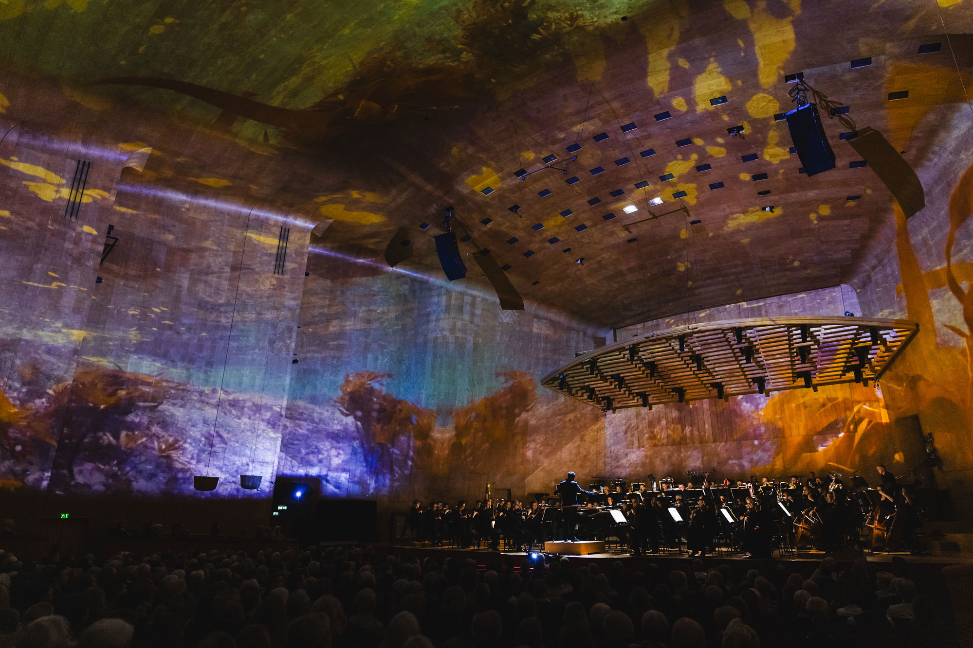 Stora salen i Göteborgs Konserthus i mäktig ljussättning med projiceringar på väggarna.