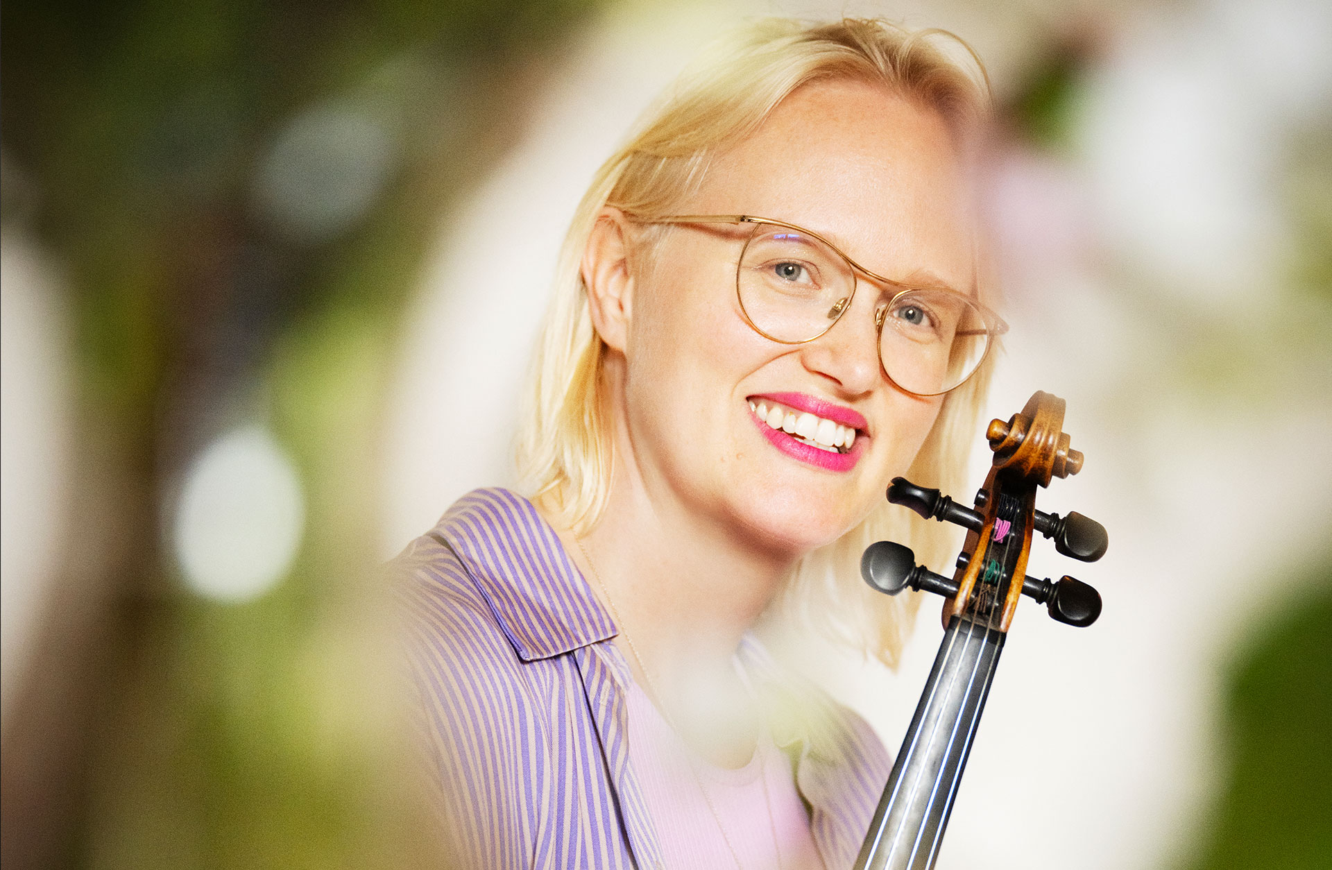 Nina, en blond kvinna med rött läppstift, ler glatt mot kameran. Hon är utomhus.