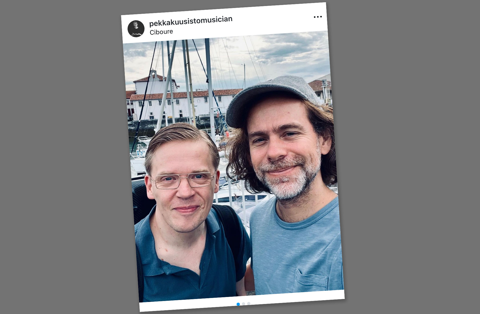 Intagambild och selfie av vännerna Pekka och Bryce som ler mot kameran. De står utomhus i en båthamn på sommaren.