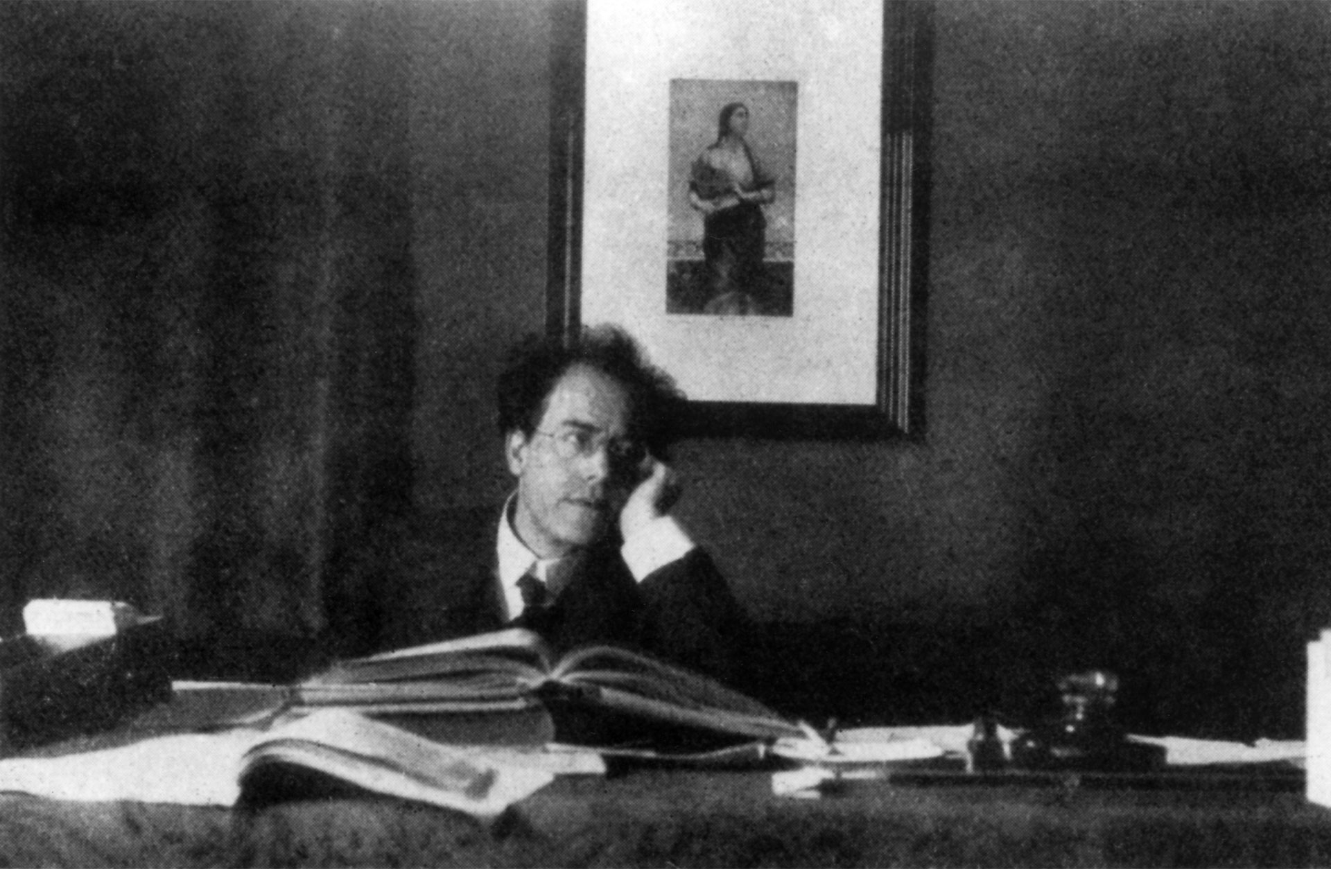 Svart vit bild där en medelålders man, Gustav Mahler, sitter vid ett skrivbord. Han stöttar huvudet i handen.