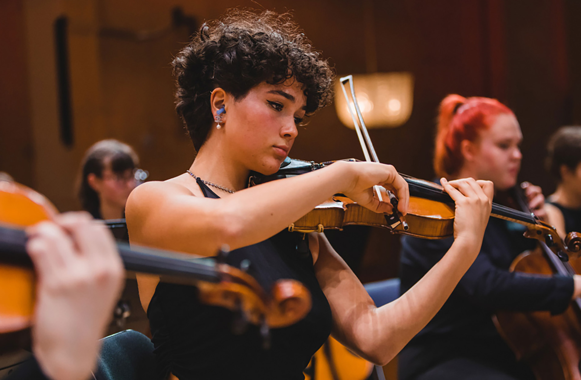 ung tjej från Västra götalands ungdomsorkester VÄGUS spelar violin på scen