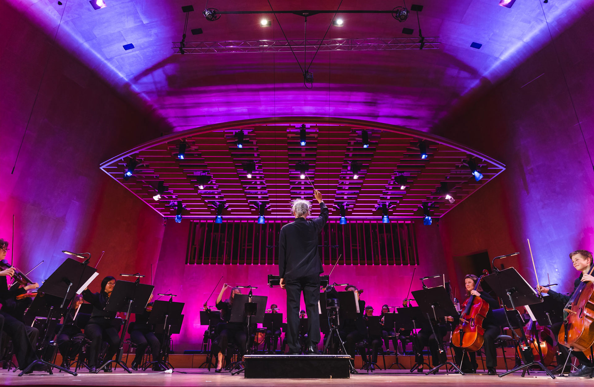 Konsert med ungdomsorkestern VÄGUS på Stora salens scen i Göteborgs Konserthus. Kim Phipps står på pulten med ryggen vänd mot publiken och kameran.